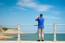 man taking a picture over a railing 