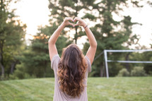 A girl forming a heart with her hands.