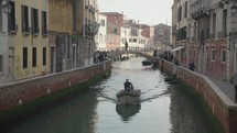 The atmosphere of narrow canals in the city of Venice, with many bridges and small boats parked.