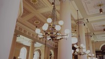 Inside of an old cathedral church looking up at a chandelier, columns and beautiful artwork during mass.