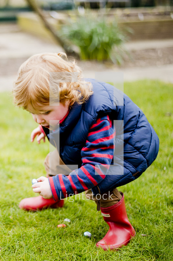 Child finding Easter eggs in the grass.