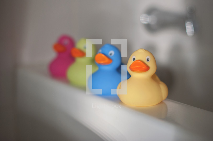 row of rubber duckies on a bath tub 