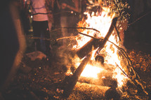 adding sticks to a camp fire 