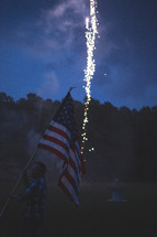 man holding an American flag in front of fireworks 