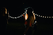 a woman outdoors and strings of lights 