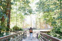 a woman with a backpack walking in a park 