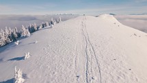 Winter mountain trail with tourist on top of the snowy hill with beautiful view of misty nature Outdoor background Aerial
