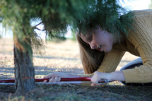 a woman sawing down a Christmas tree 