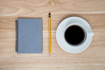 spiral notebook, pencil, and coffee cup 