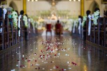 rose petals in the aisle of a church at a wedding 