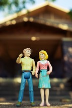 Plastic toy couple in front of a house