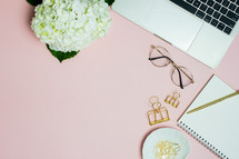 pink computer desk with notebook and hydrangeas 