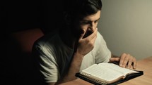 man praying and reading a Bible 