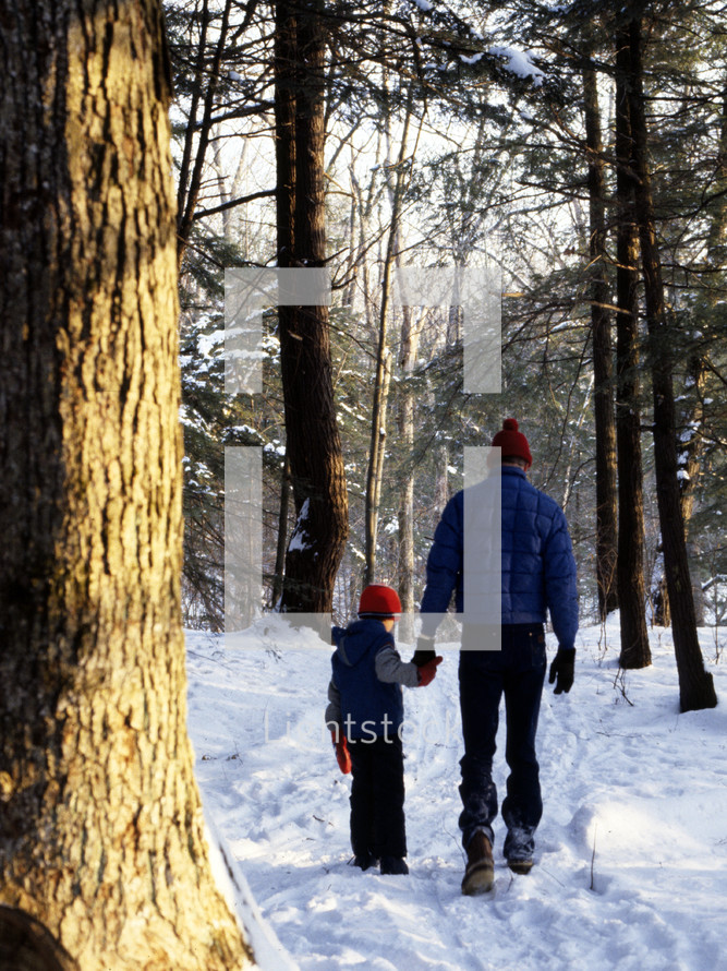 father and son walking in a forest in the snow 