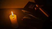 Candle with the cross on Bible on wooden table in the night. worship prayer and bible study concept.