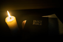 Close up Candle with the Bible on wooden table in the night. worship prayer and bible study concept.