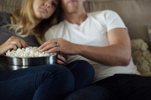 movie night, a couple watching tv together with a big bowl of popcorn 