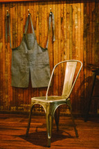 A apron hanging on a hook and a chair. 