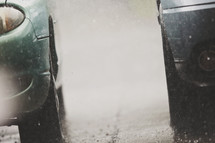 downpour of rain bounces off the pavement between 2 cars