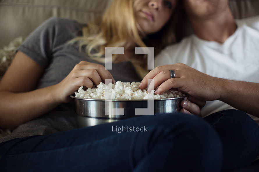 movie night, a couple watching tv together with a big bowl of popcorn 