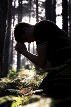 man praying in a forest