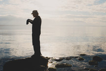 man with binoculars on rocky coast of the ocean