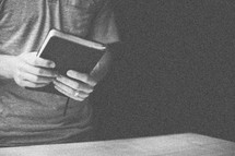 Man's hands holding a closed Bible.