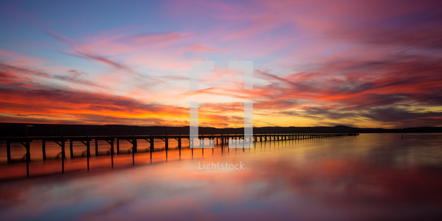 pink sky over a pier at sunset 
