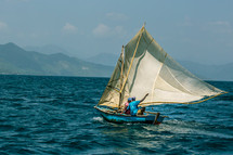 men fishing in a sailboat on the ocean 