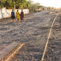 women walking on a dirt road next to tracks in Africa 