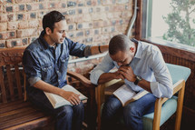 men with heads bowed in prayer at a Bible study 