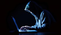 Hooded hacker stealing information from a laptop computer.