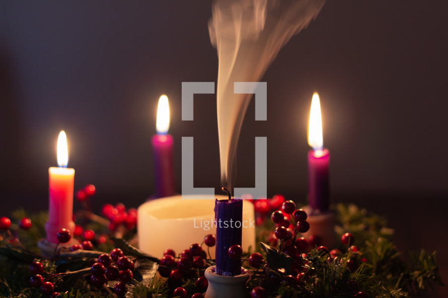 advent wreath with four candles and one blown out 