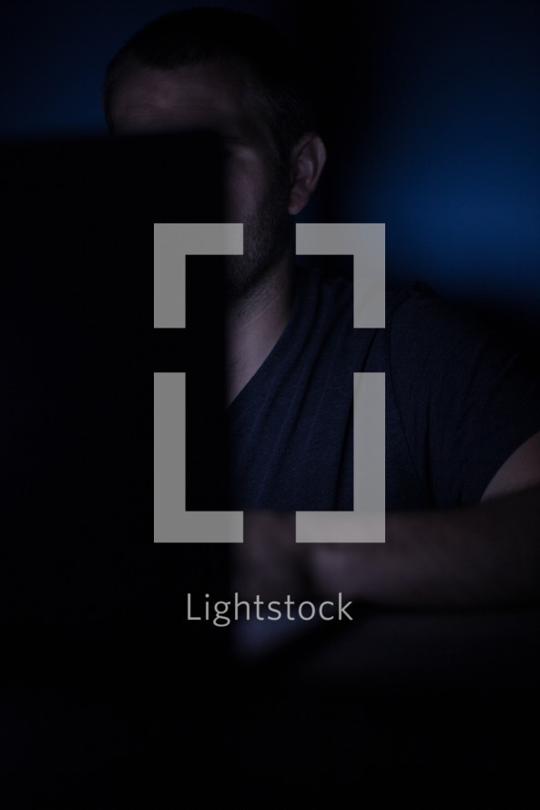 a man looking at a computer screen at night 