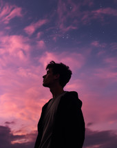A young man looking looking up toward the sky during sunset