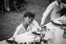 a boy child sitting at a table at a dinner party 