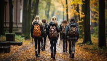 Group of young women with backpacks walking through the autumn park.
