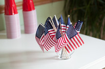 American flags in a vase and red cups 