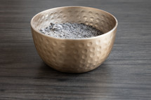 Bowl of ashes on a dark wood background with copy space 