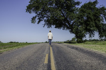 man standing in the middle of a road with his back to the camera 