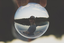 a man's reflection in a glass ball 