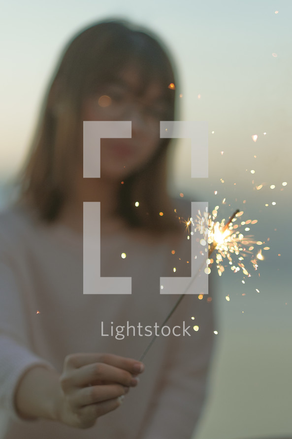 young woman holding a sparkler 