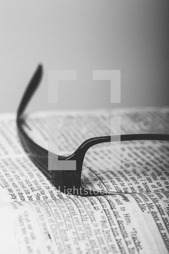 Reading glasses on pages of open Bible.