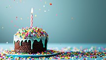 Birthday cake with candle and colorful sprinkles on a blue background