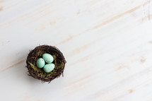 eggs in a bird's nest on a white wood background 