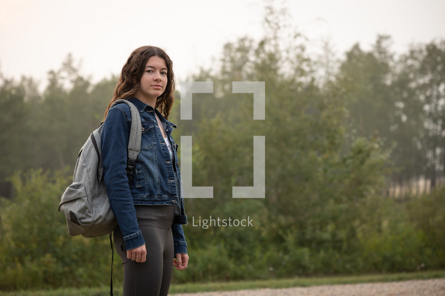 teen girl standing outdoors with a backpack 