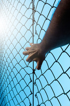 hand grabbing a metallic fence, feeling free