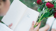 a woman reading a book holding a bouquet of flowers
