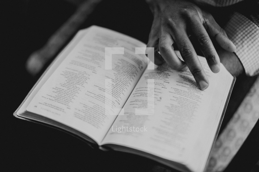 man's hand on the pages of a Bible 