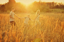 siblings holding hands walking in a field
